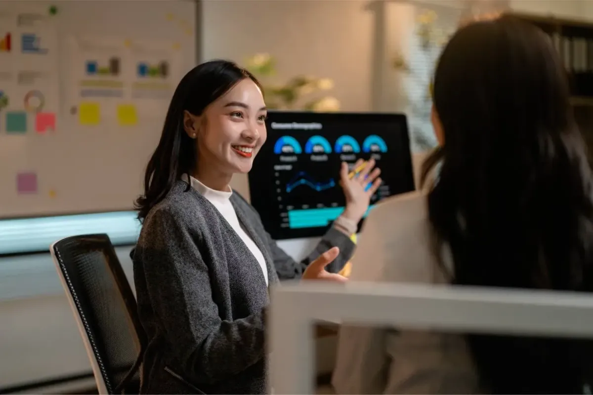 Smiling woman presents a tablet screen clearly displaying a comprehensive data report with charts.