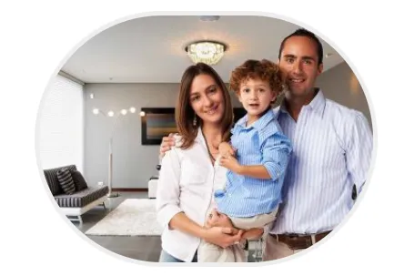 Oval-shaped portrait of a smiling family (mother, father, and two young boys) standing together in a brightly lit living room