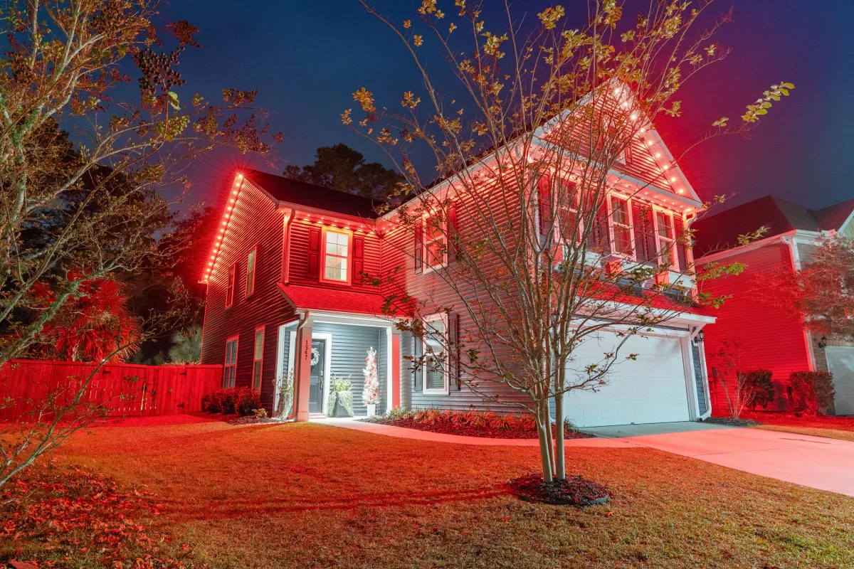 Front-facing view of a house adorned with red and white EverBright permanent Christmas lighting along the roofline.