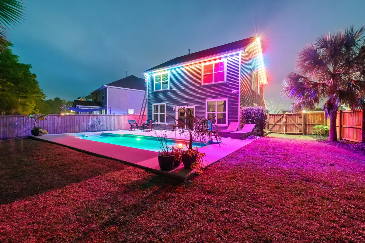 Backyard illuminated with Govee Permanent Lights in pink and white, highlighting a poolside setup with smart home compatibility for custom routines.