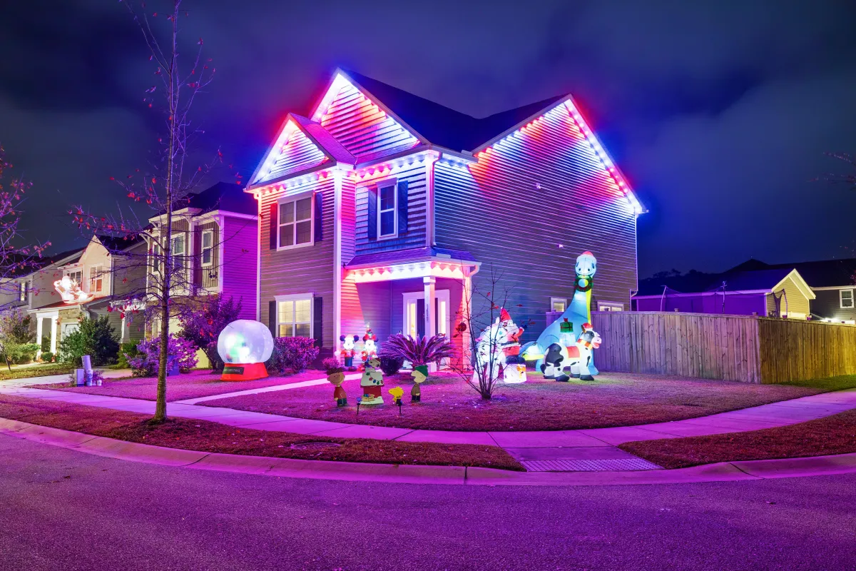 Two-story home with multi-colored EverBright permanent holiday lights and festive decorations in the yard.