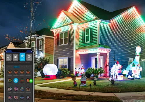 Two-story home illuminated with vibrant, customizable LED holiday lights controlled via a smartphone app shown in the foreground.