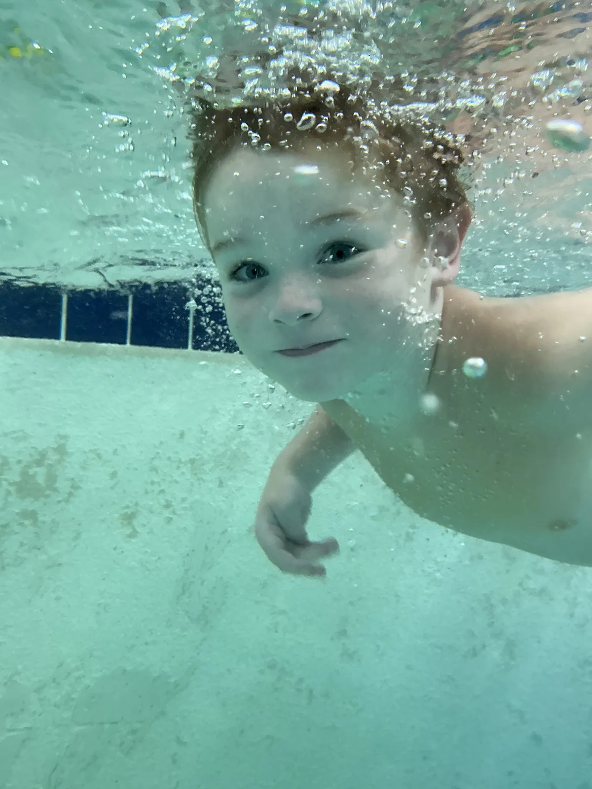 A coach and a smiling swimmer play together in the warm water