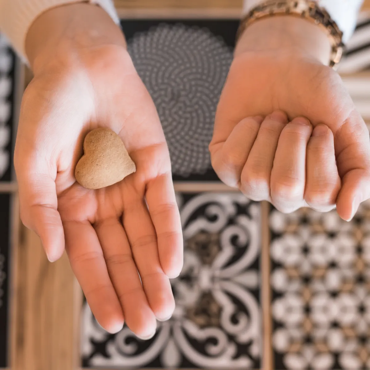 Open hands holding a heart-shaped stone representing self-compassion and mindset healing.