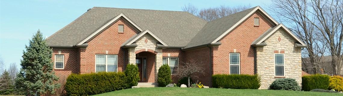 Brick and stone ranch-style home with a green lawn under a blue sky in Lubbock, TX