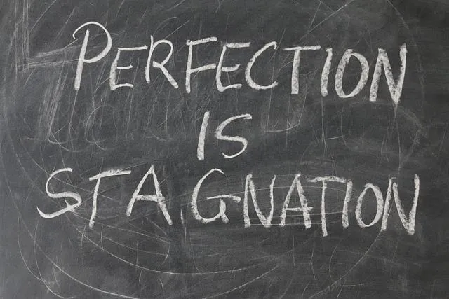 A blackboard with the phrase perfection is stagnation written on it