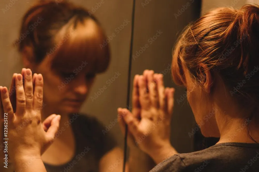 A woman struggling mentally with her palms on a bathroom mirror.