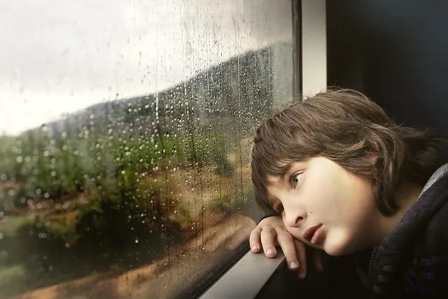 A sad boy looking out a train window