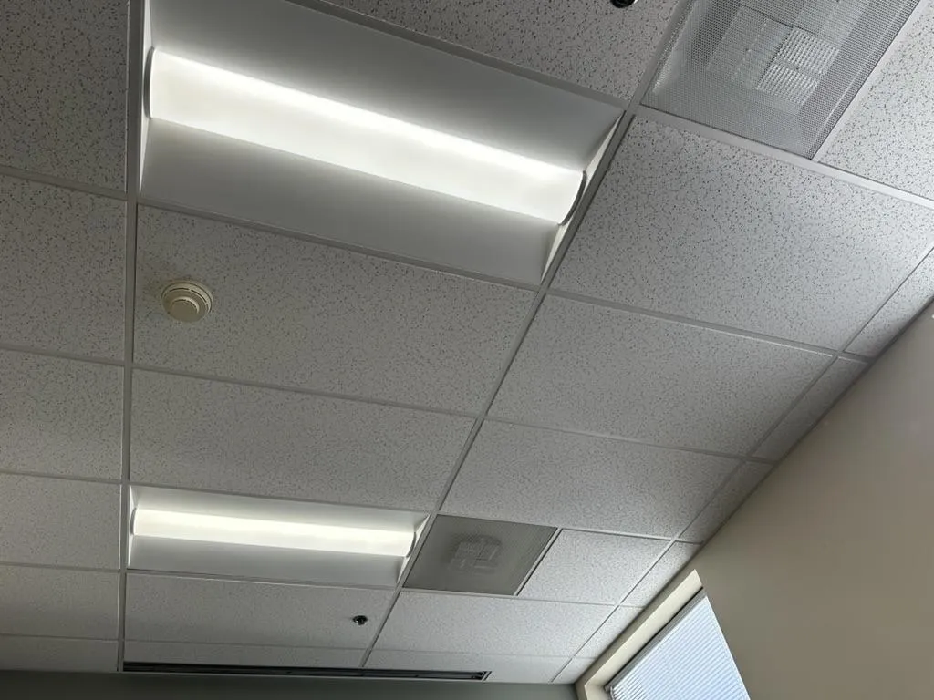 Electrician installing lighting system and power controls in an office ceiling