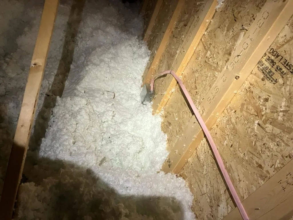 Electrician addressing electrical emergency in attic space with insulation