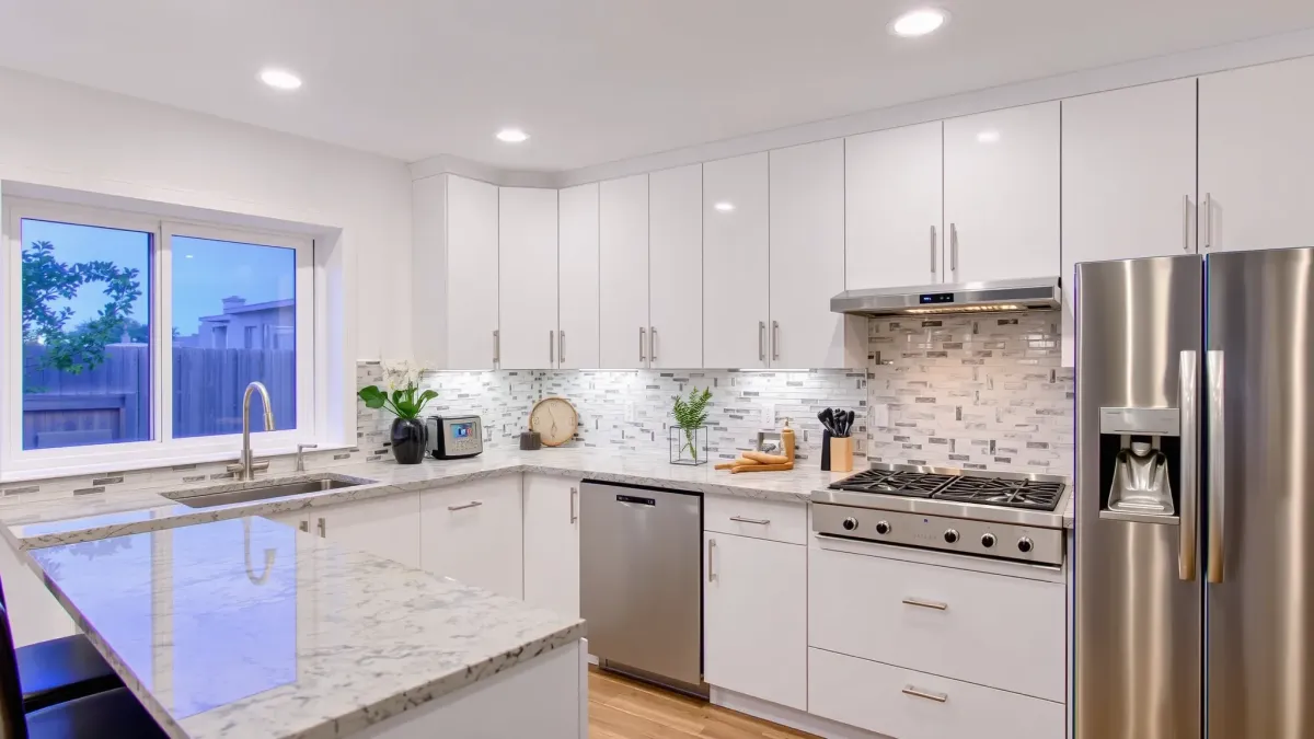 San Clemente coastal-inspired kitchen with wooden cabinets, stainless steel appliances, granite island, and natural sunlight.