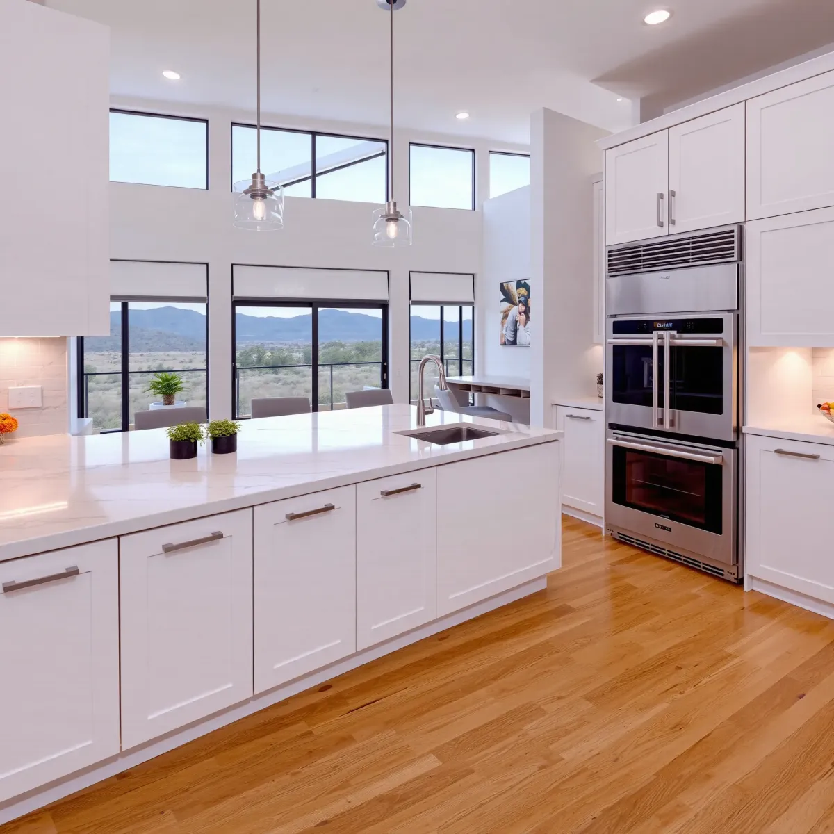 Modern remodeled kitchen in MainPlace, CA with white cabinets, marble island, high-end appliances, hardwood floors, and natural light.