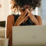 A confident mid-career manager in a bright conference room, calming a tense discussion while holding a tablet with the Hearthbridge playbook open.