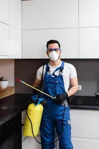 a cVancouver pest control technician standing in a kitchen holding a pest spay