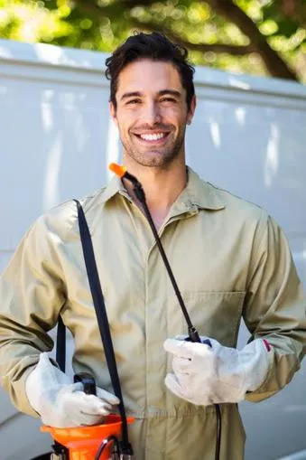 a Vancouver pest control technician holding pest spray and stood in a kitchen smiling at the camera