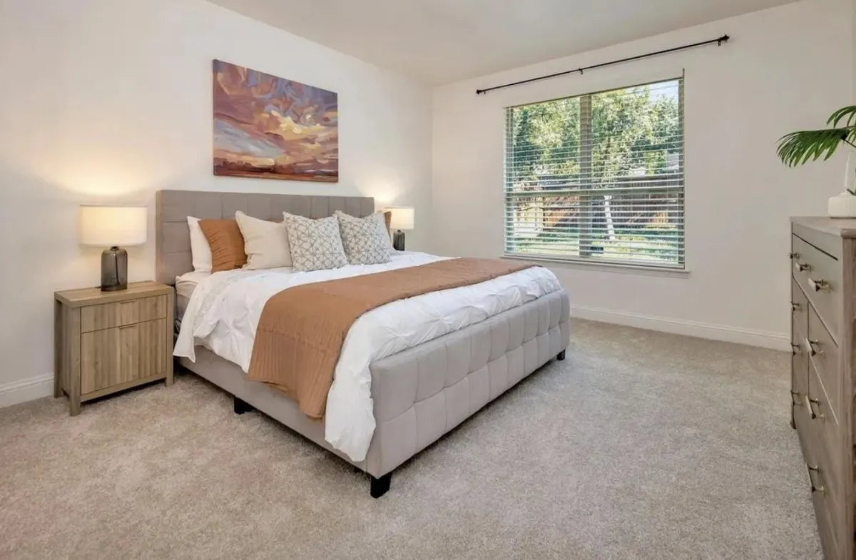 Bright secondary bedroom with a large bed and spacious layout, professionally staged by Model My Home—Dallas Fort Worth home staging and design experts.