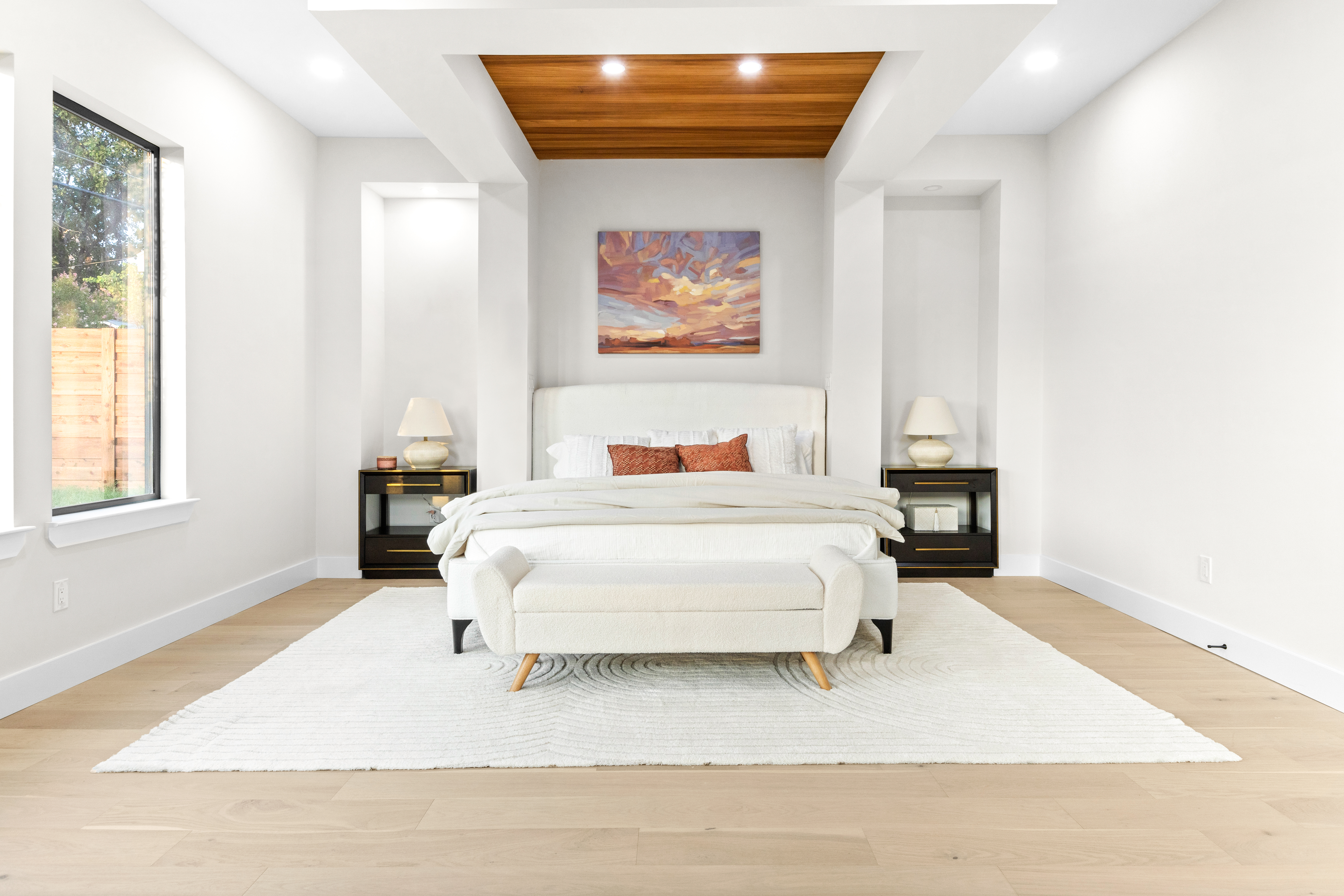 Bright white primary bedroom featuring decorative wall cutouts and a wood panel ceiling accent above the bed, professionally staged by Model My Home—Dallas Fort Worth home staging and interior design experts.