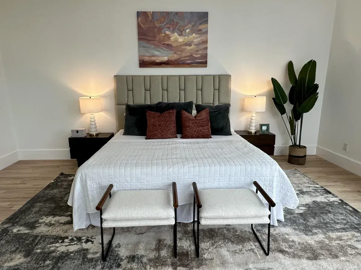 Bright neutral toned bedroom with maroon accent colors and an olive plant