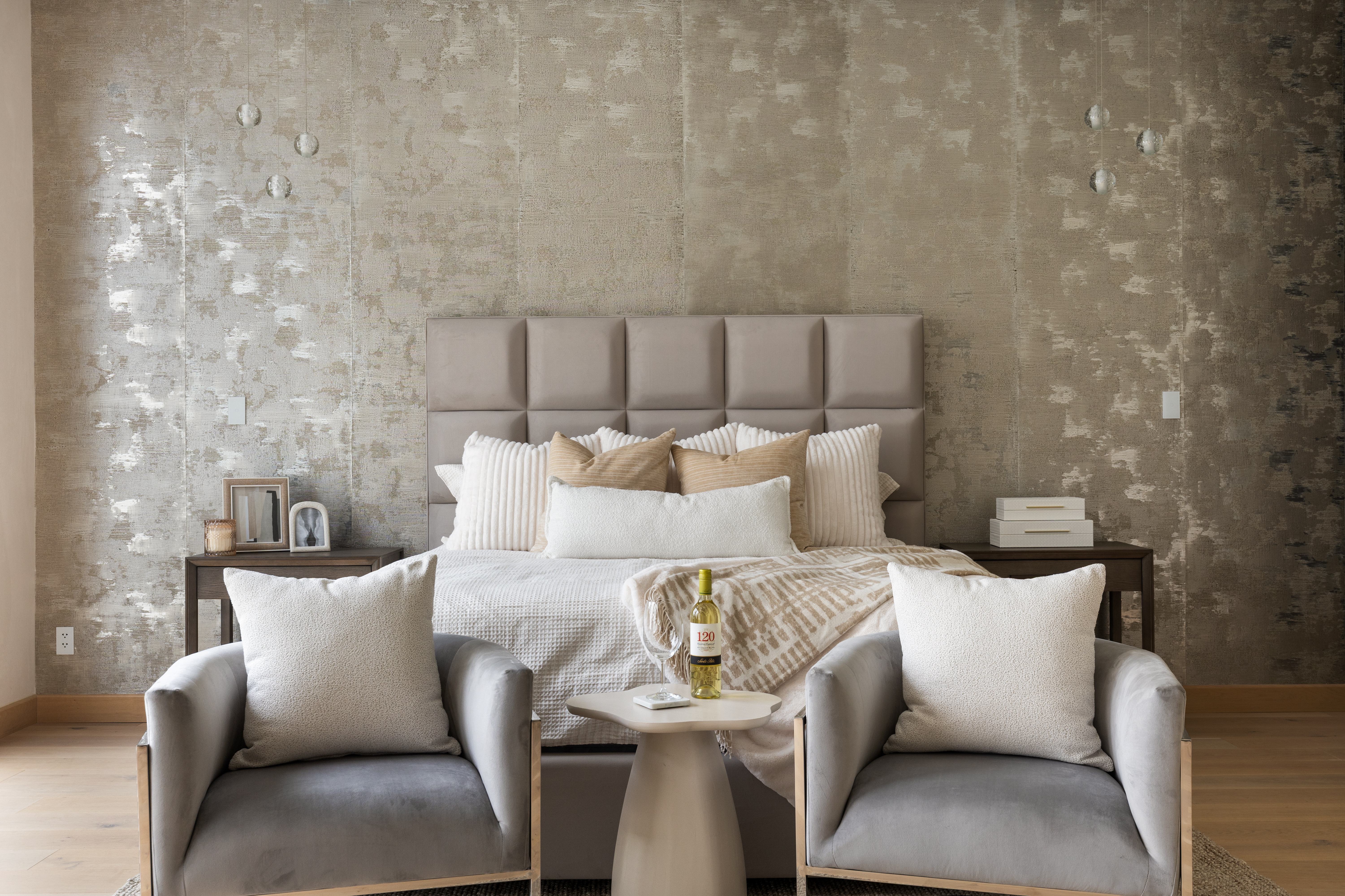 Luxury primary bedroom featuring a stylish accent wall and a comfortable sitting area at the end of the bed, professionally staged by Model My Home—Dallas Fort Worth home staging and interior design experts.