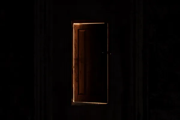 A wooden door slightly open with warm light spilling through, symbolizing an unexpected answered prayer