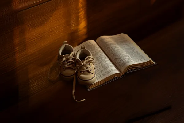 A small pair of children's shoes beside a worn open Bible in warm light, symbolizing grace and guidance in raising ministry kids