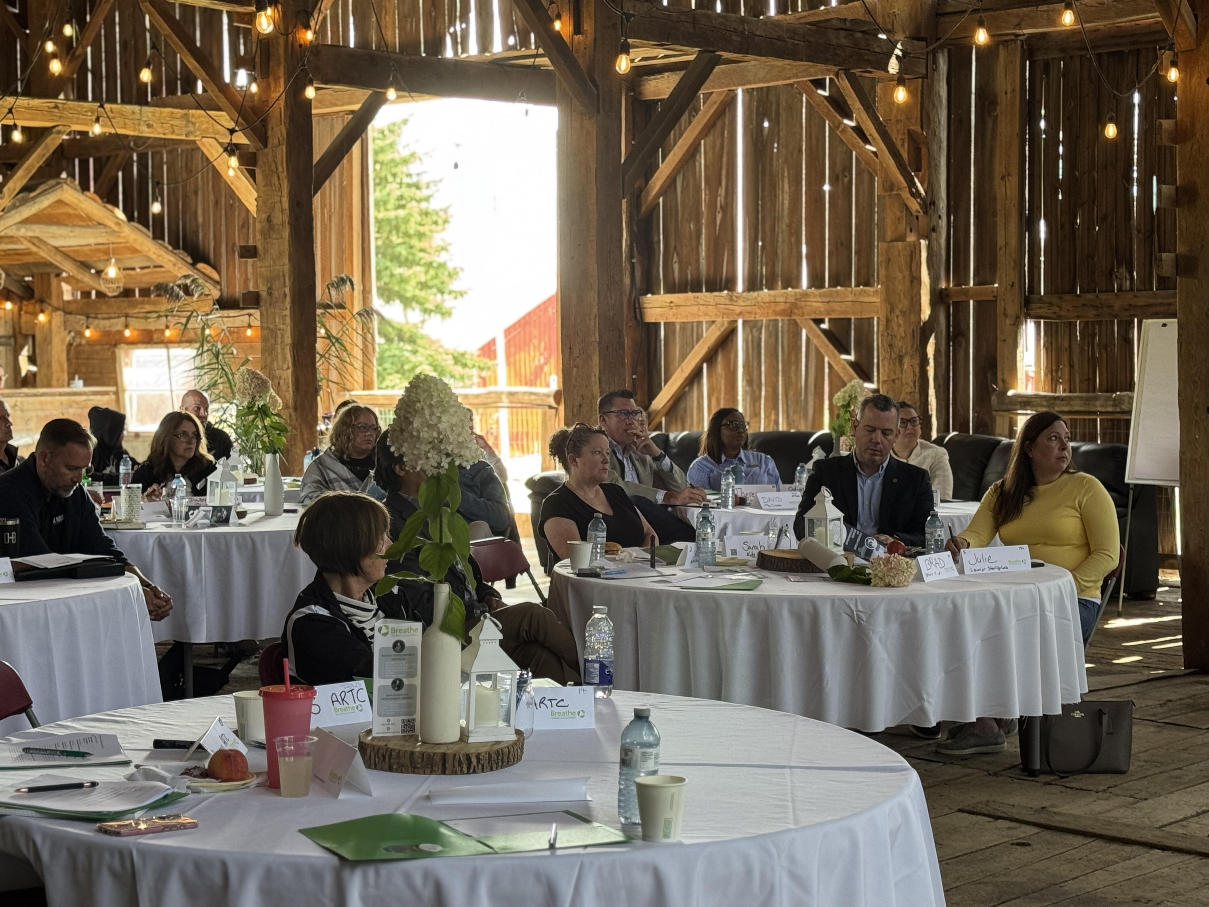 A professional, approachable support specialist at a desk, speaking on a headset, with a laptop and notepad. The background shows a bright, organized office with plants and nonprofit posters, conveying accessibility and expertise.