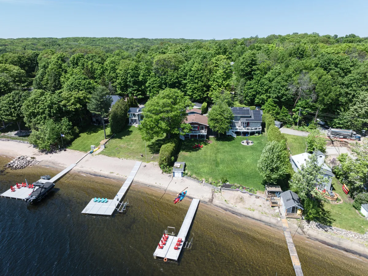 A sunny sandy beach on a Muskoka lake with clear blue water and Canadian Shield rock