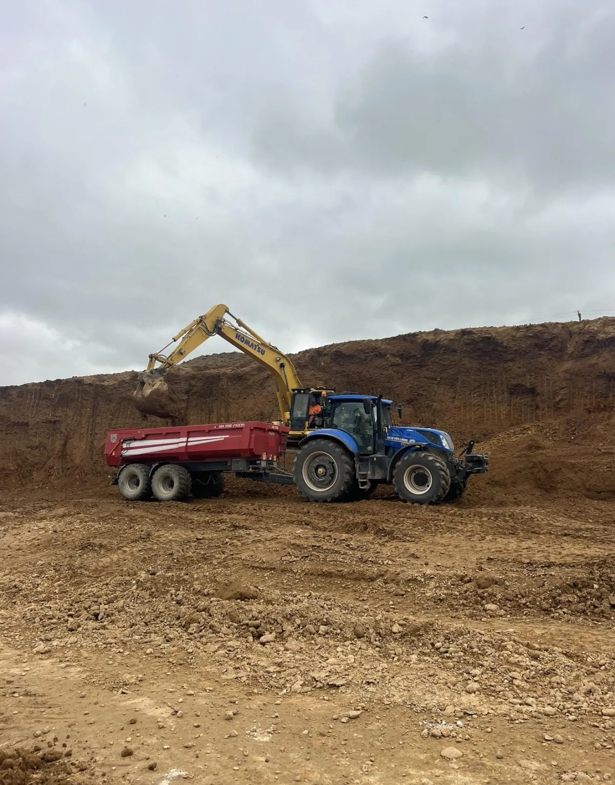 Excavator loading soil into tip trailer during a land prep job