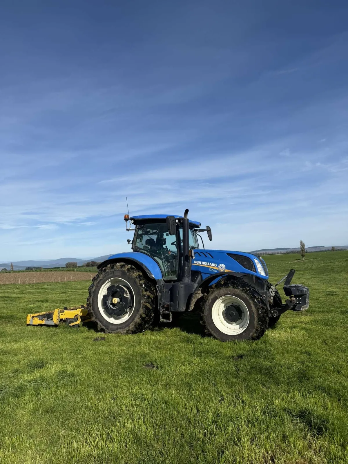 Tractor performing aerating work on a lush green pasture