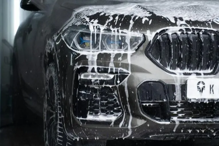 bilens panser med en microfiberklut, i et moderne bilpleieverksted, illustrerer profesjonell bilvask og pleie hos Selma Bilpleie.