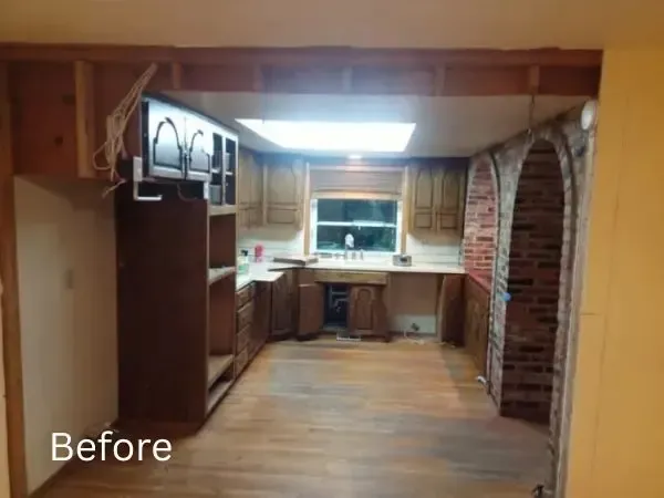 The before view of a basement kitchen remodel with a giant brick wall that was eventually removed.