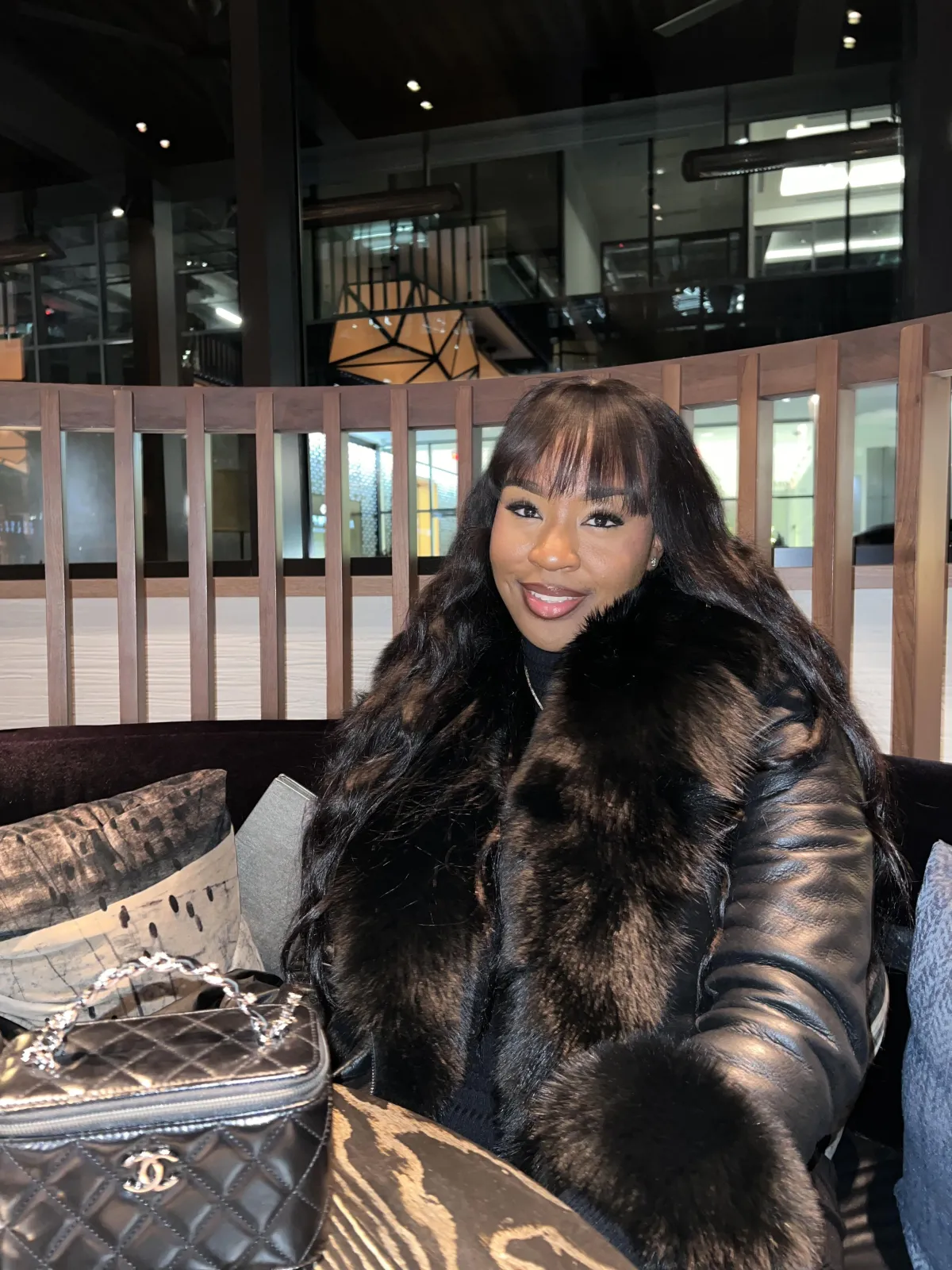 Senior Asian-American woman with silver hair, wearing a navy blazer, smiling warmly in a sophisticated office. The background features abstract art and a marble desk, exuding authority and approachability. 1:1 aspect ratio.