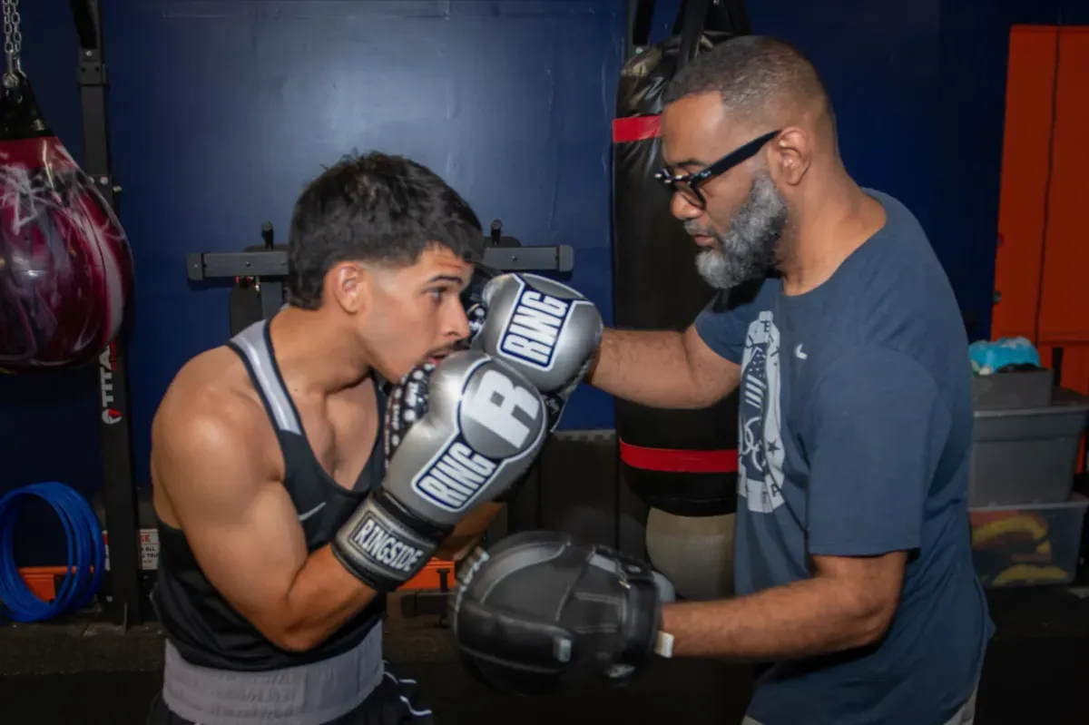 man in black talking to boxer inside ring