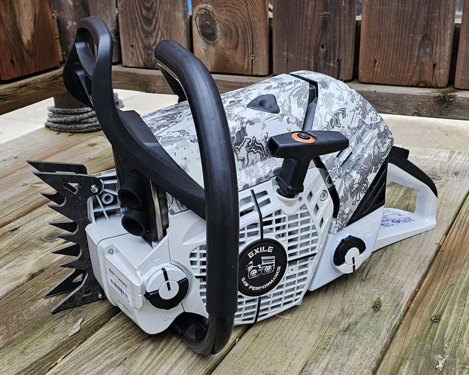 Custom hydro-dipped chainsaw with grey digital camo pattern on deck boards