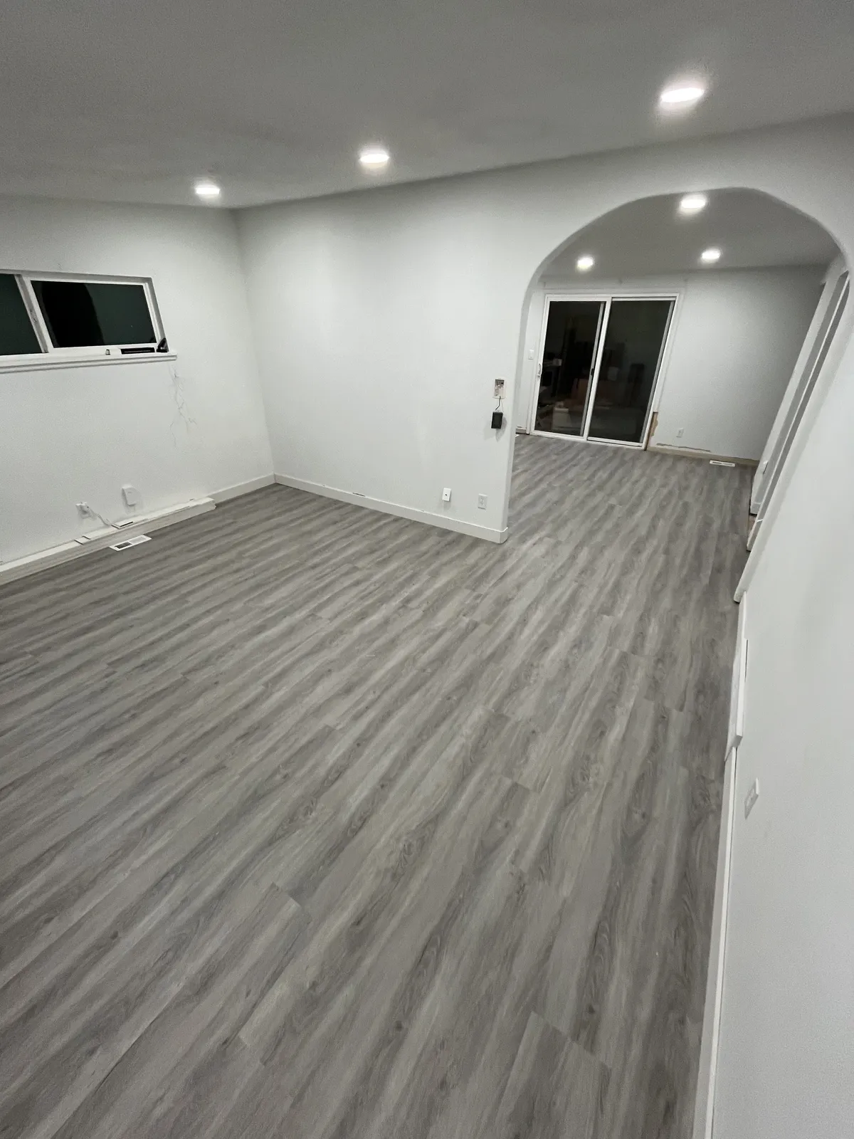 Living room with newly installed gray luxury vinyl plank flooring and an arched doorway