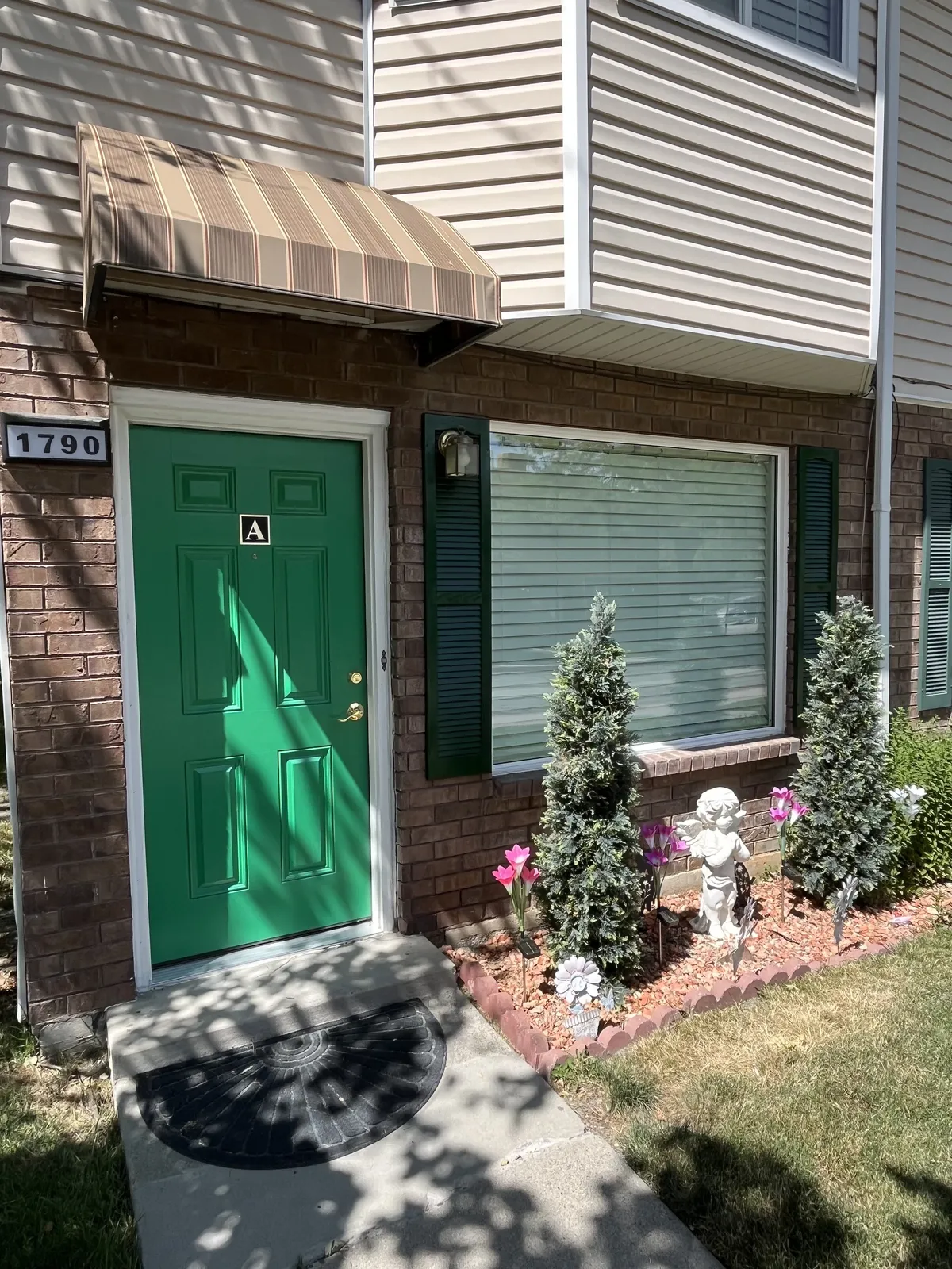 Green front door with brick surround and landscaped entry
