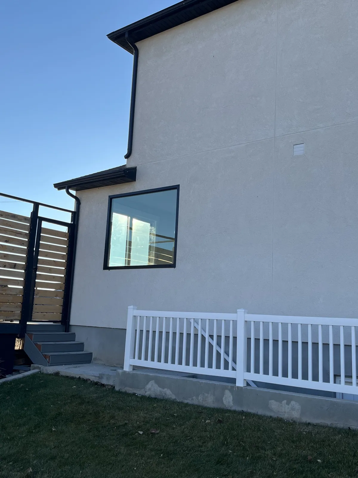 New black-framed window on a stucco home exterior