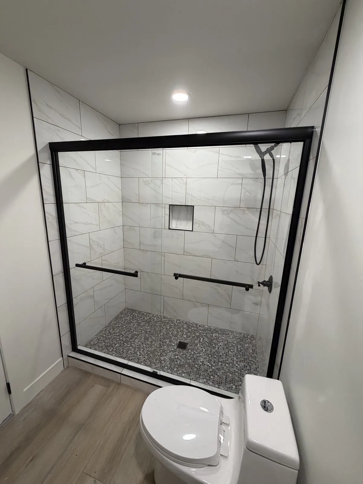 Black-framed sliding glass door on a tiled shower