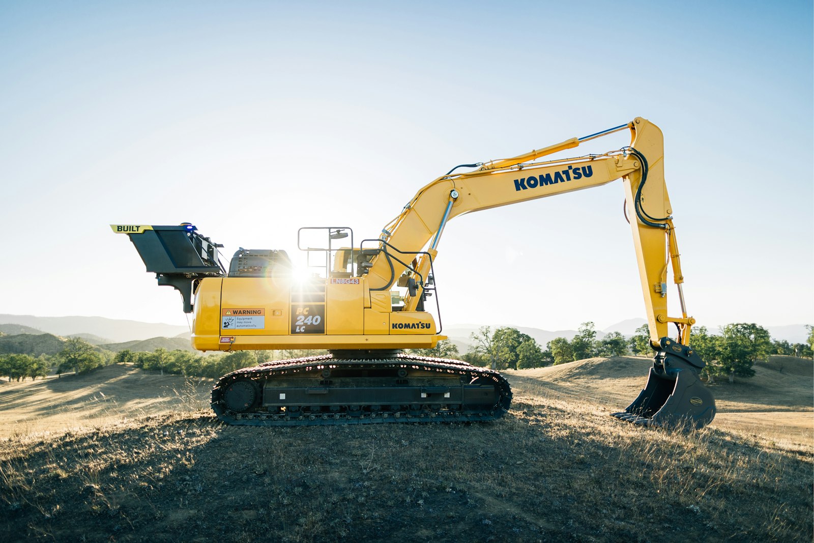 Excavator working a cleared, rolling rural acreage tract being prepped for a build