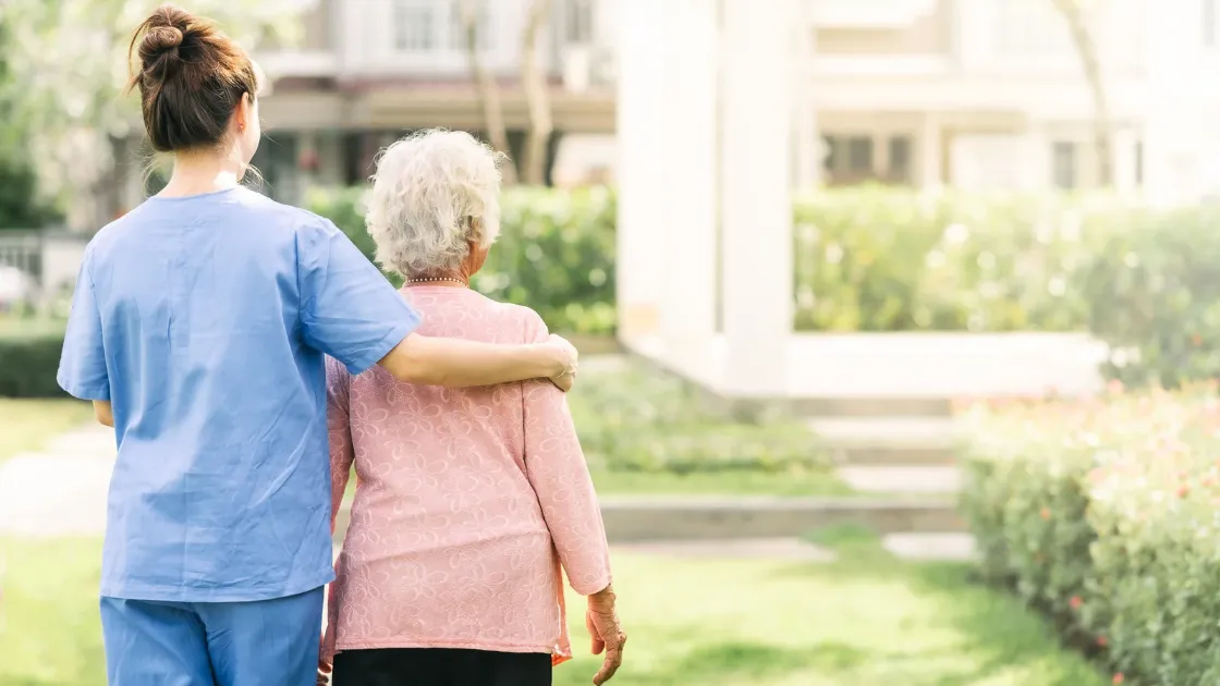 Caregiver walking with an elderly woman outdoors