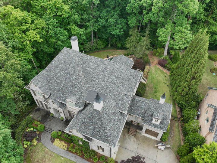 Residential roof repair project in Covington, Georgia completed by Elite Roofing & Outdoor Construction with fresh gray shingles and surrounding trees