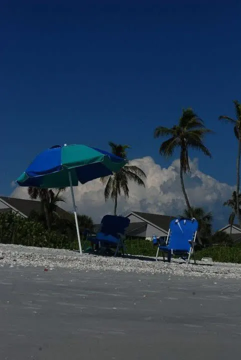 Spacious master suite with king bed, luxury linens, and a balcony view of the Gulf, styled in soft sand and seafoam tones for a restful retreat.