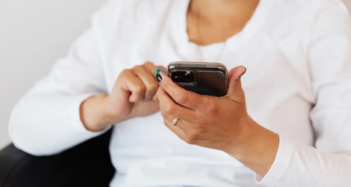 Health and wellness coach scrolling through social media content on smartphone, wondering why engagement isn't converting to consultation bookings