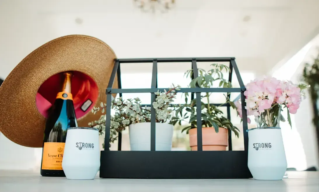 Strong Landscaping welcome gift with champagne, branded tumblers, and fresh flowers