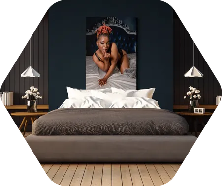 A boudoir photo of a woman posing in lingerie on a bed. The picture is hanging on the wall in a master bedroom.