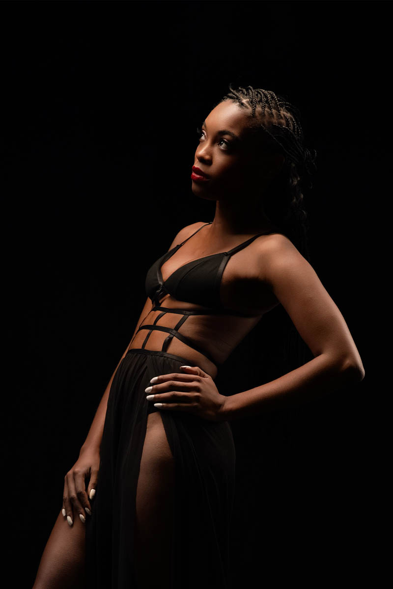 Woman in black lingerie against dark background with soft light, boudoir portrait