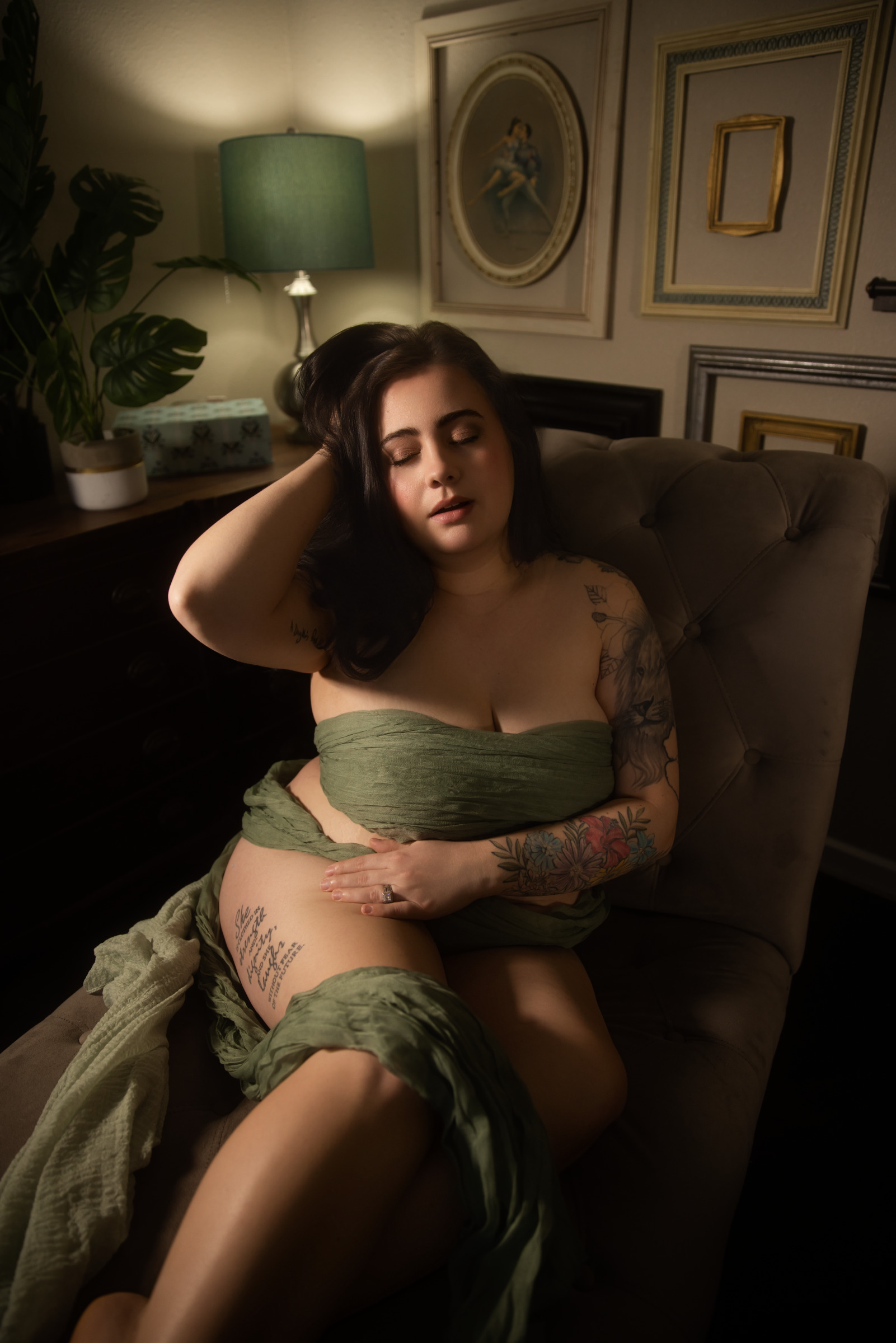 Woman holding denim jacket over face with playful expression during boudoir session