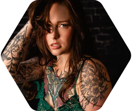 A brunette woman with ornate tattoos in lingerie poses for a boudoir shoot in Indianapolis at Enchanted Moments Artistry