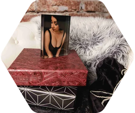 A picture of a woman in lingerie posing for a boudoir shoot. The picture is placed on books by a bed.