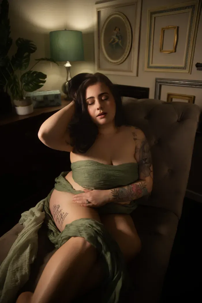 Woman in a green wrap seated in a velvet armchair, moody boudoir portrait Indianapolis